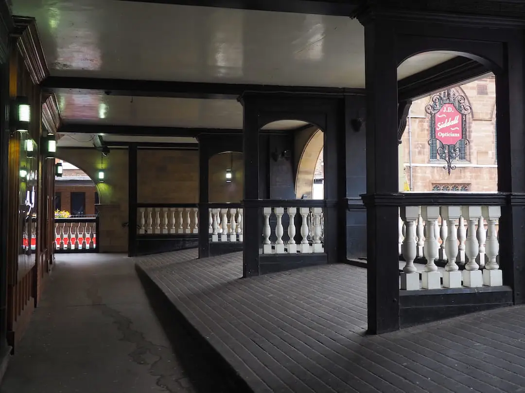 Am enclosed passageway with railings above the street to the right