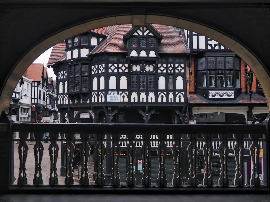 View of a black and white half-timbered building through an arch