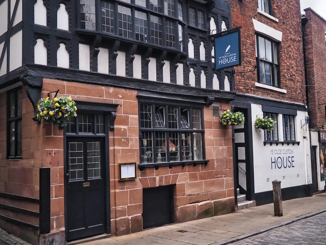 A sandstone building with a black and white half-timbered facade on the first floor