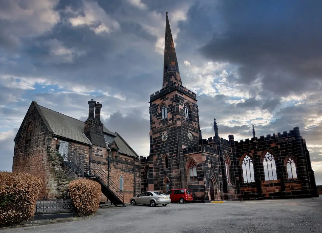 An old building with tower and spire and arched windows to the left