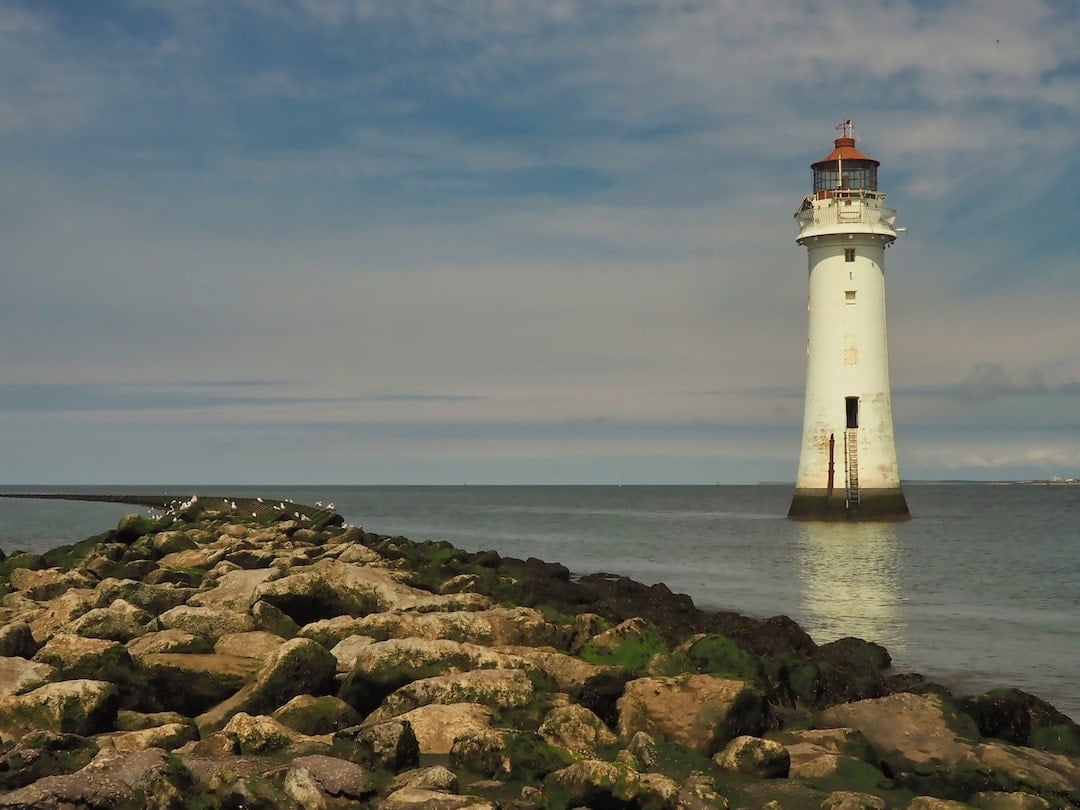 A pavement of rocks runs into the background with a white lighthouse to the right