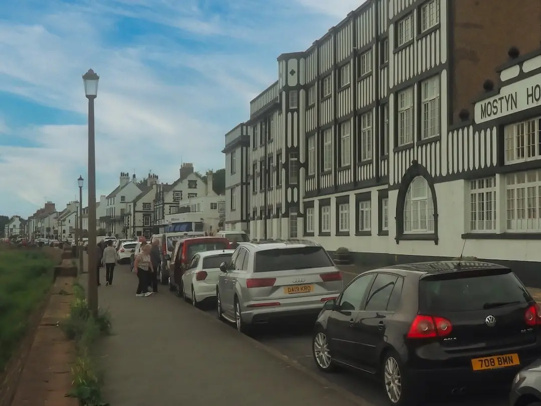 A row of cars parked on the left and a black and white building on the right