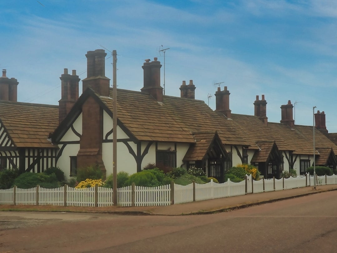 A row of cottages surrounded by low white fencing