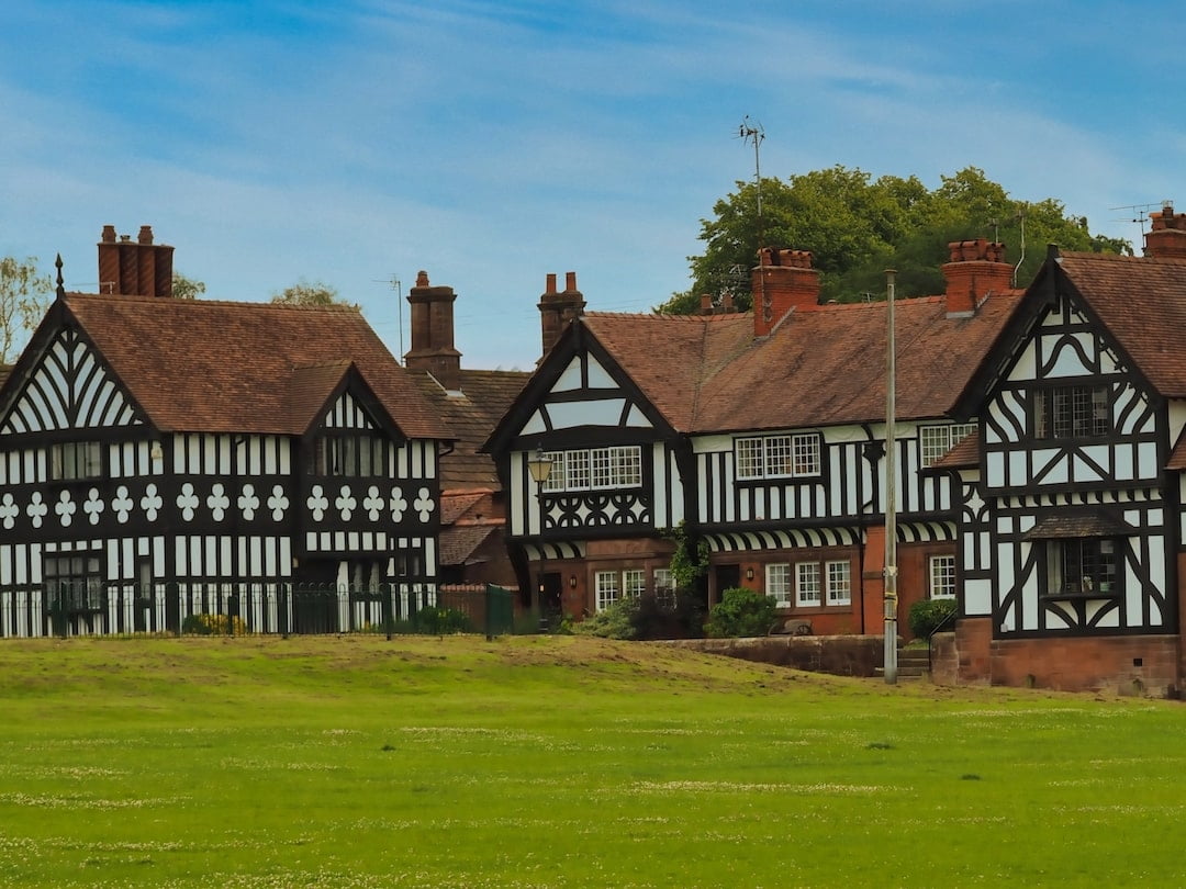 A grassy area in the foreground with black-and-white half-timbered buildings in the background