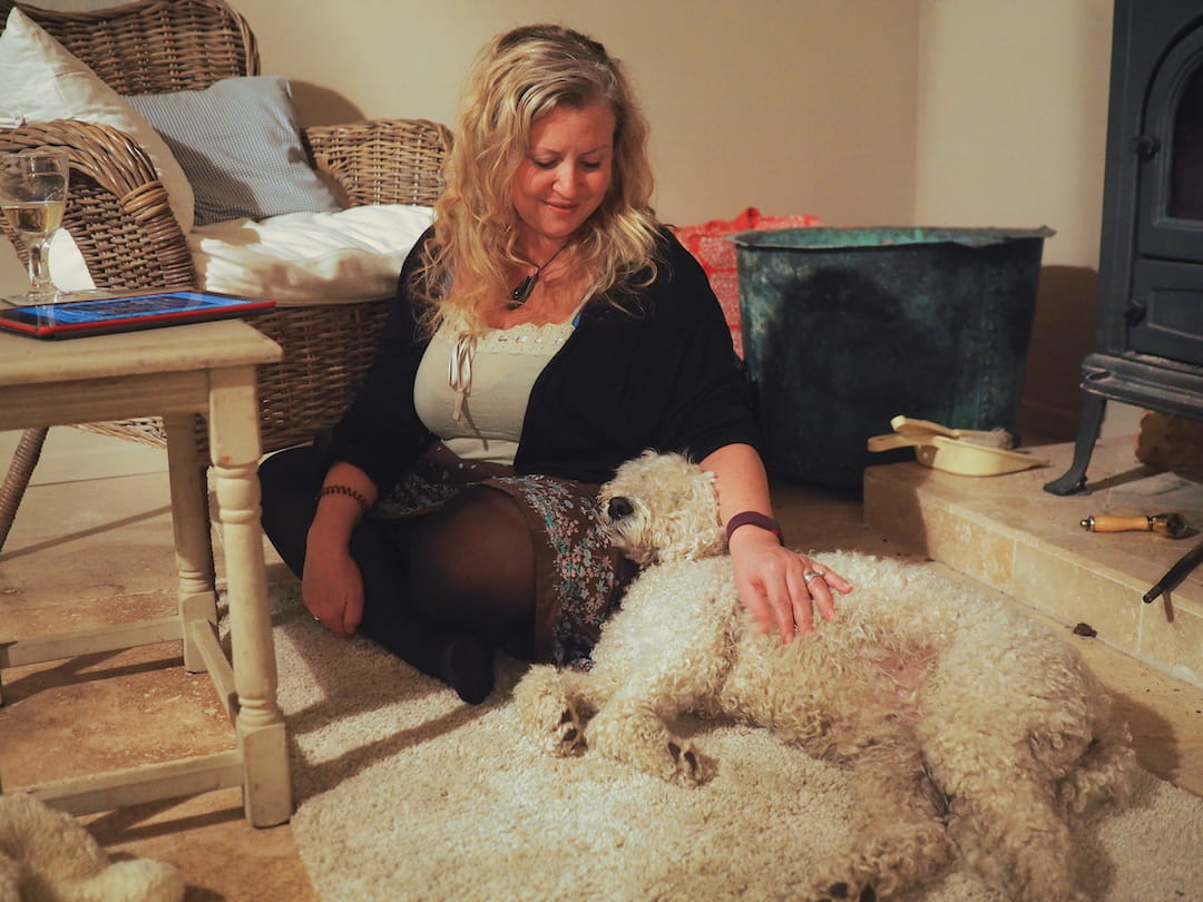 A dog lies against a woman seated on a rug