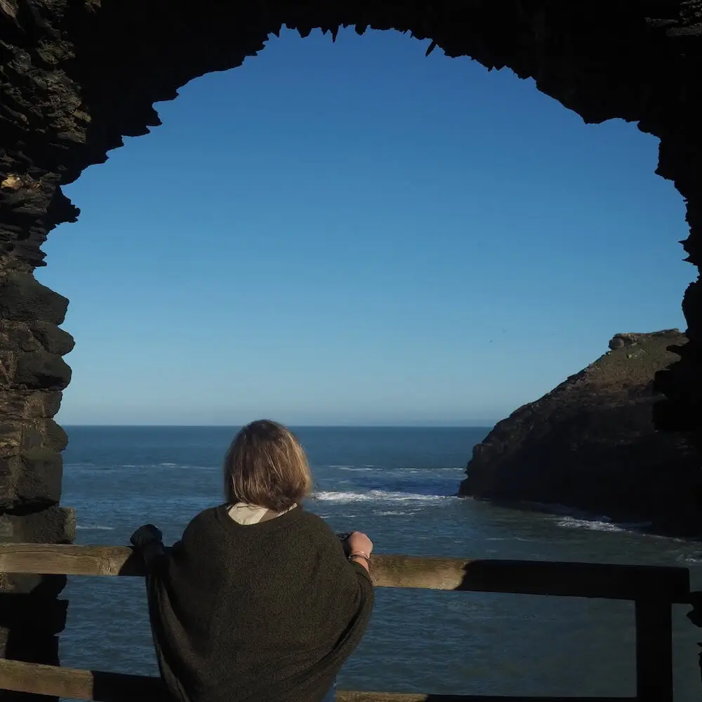 Tintagel Island - Nicky A woman looks out to sea through a natural window in a stone wall