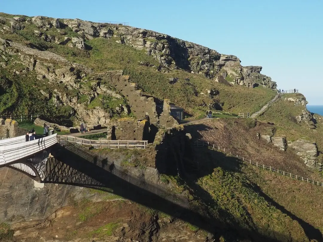Tintagel Island A white bridge connects with an island featuring green hillside and craggy rock