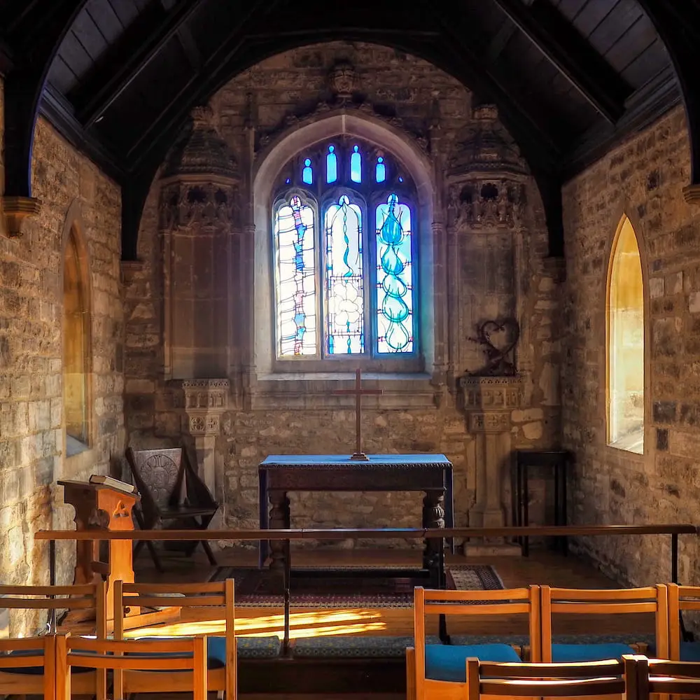 A stone church interior with painted glass window in the background