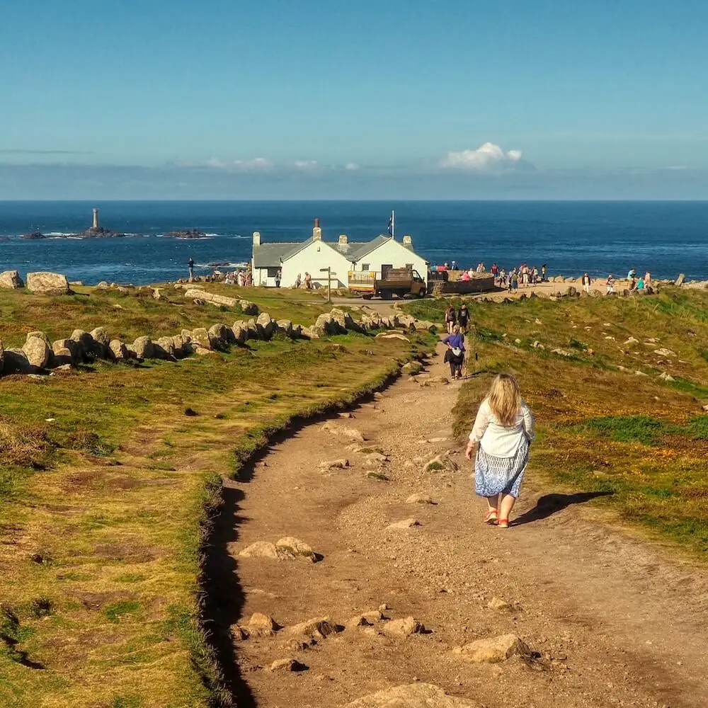 Lands End - Approaching The First And Last House. A footpath leads to a white building above cliffs and the sea