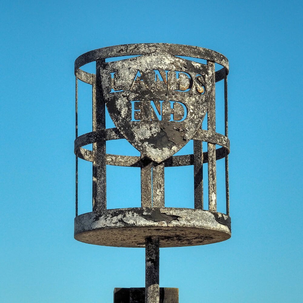 A metal drum-shaped sign with the words "Lands End" and blue sky as a background