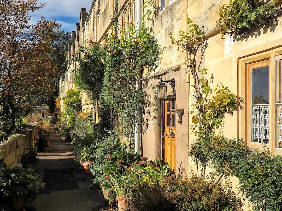 Stone terraced houses behind a narrow footpath and surrounded by foliage