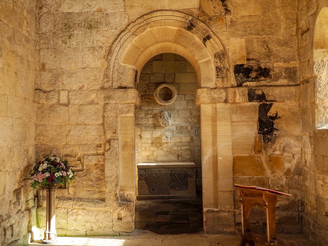 Stone interior of a church with an archway leading through to a small room