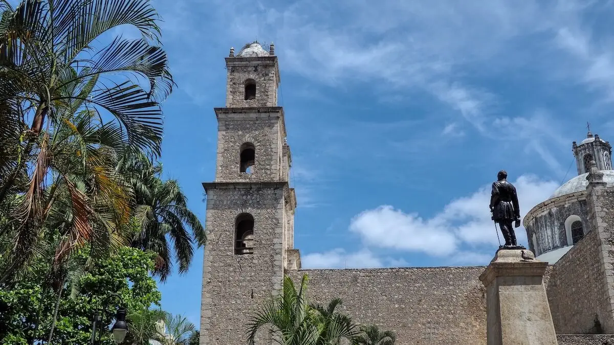 A statue looks up to the tower of a church on Parque Hidalgo