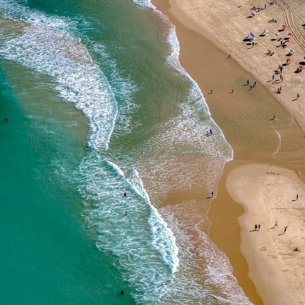 Turquoise sea, white surf and golden sand as viewed from above