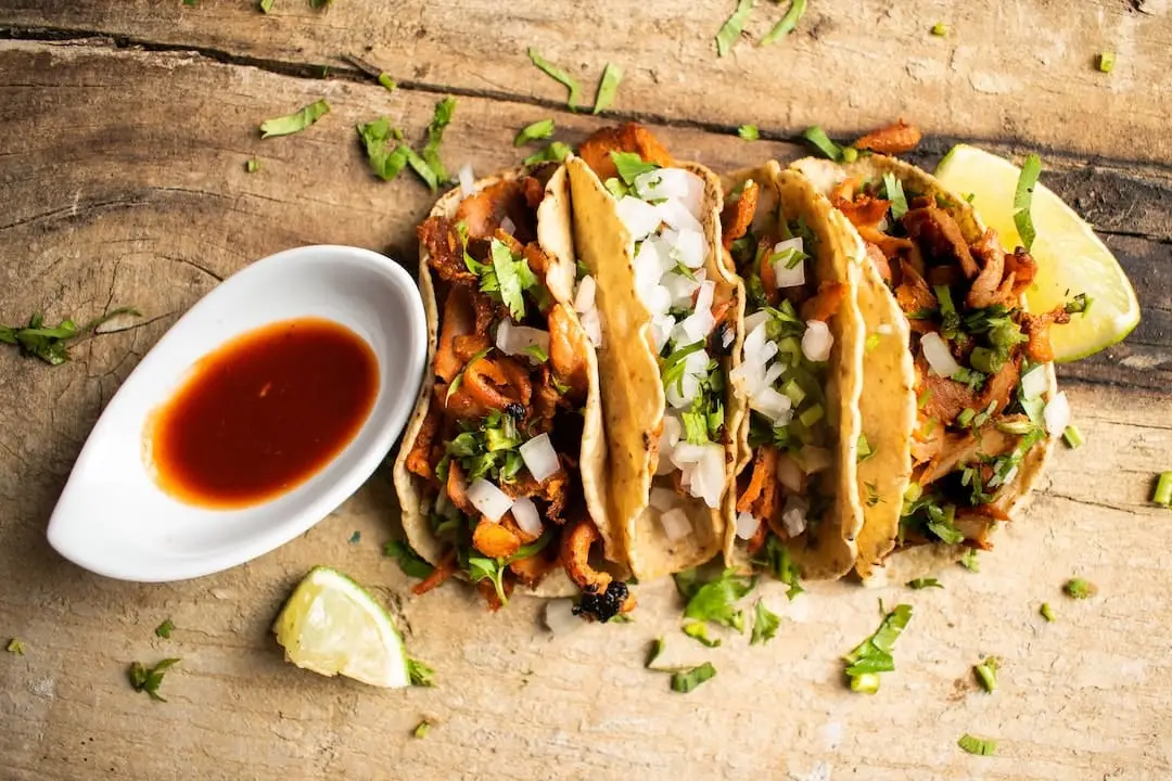 Three filled tacos and sauce on a plate