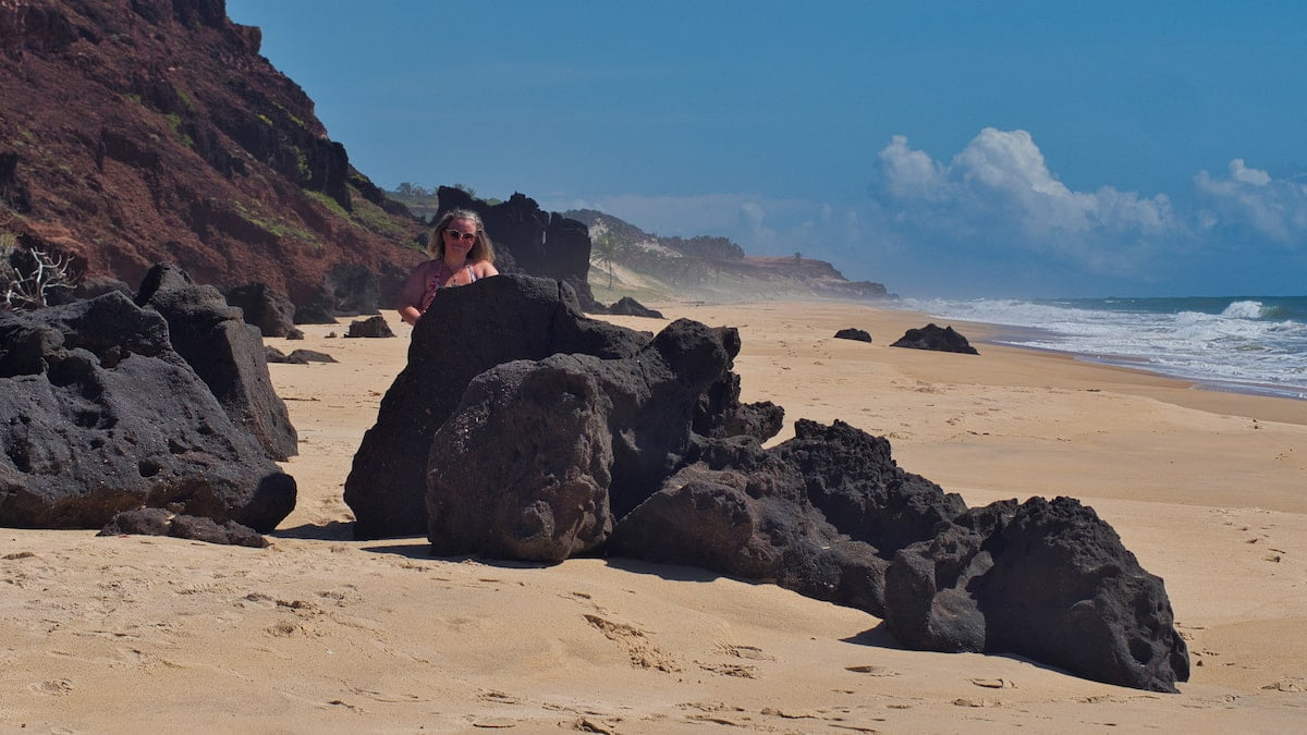 Nicky stands behind some rocks on Praia das Minas
