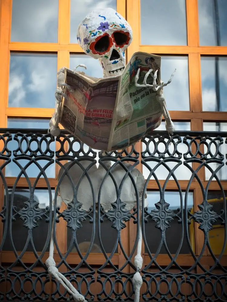 Day of the Dead skeleton reading a newspaper - Oaxaca A skeleton stands on a balcony reading a newspaper