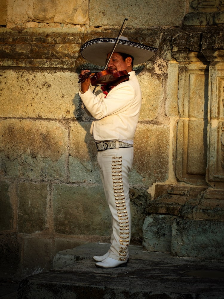 A man dressed in traditional mariachi clothes plays a violin