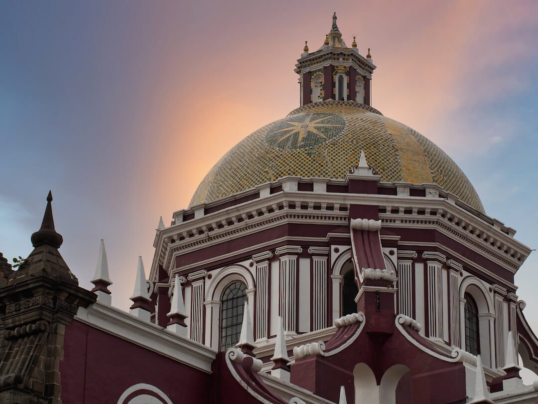 Red-coloured cathedral with a gold-coloured dome on top