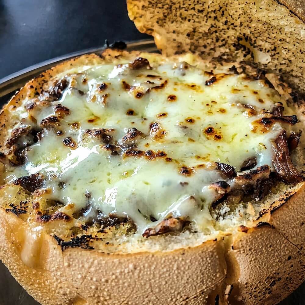 A open toasted bread roll topped with meat and melted cheese
