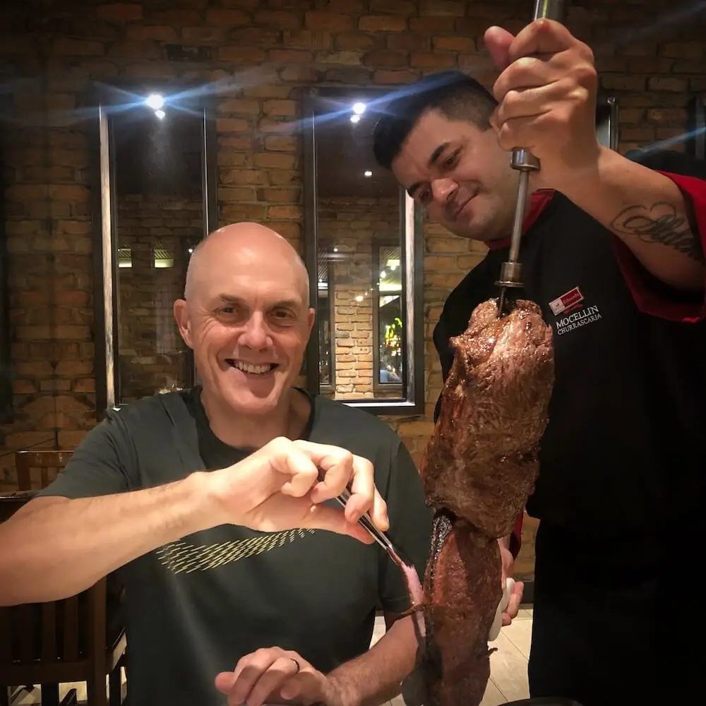 Ian watches on while a waiter carves meat from a skewer