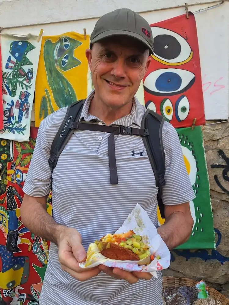 Ian stands while holding an acaraje