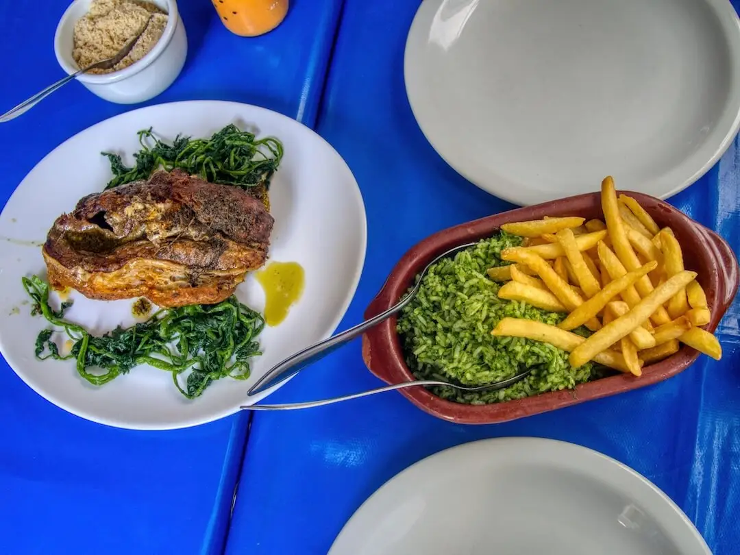 Separate plates of meat, green rice and fries