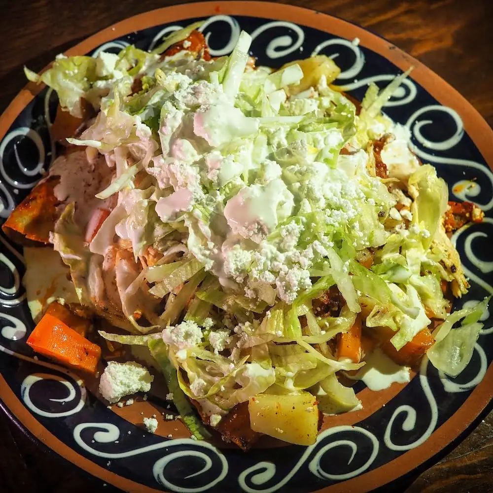 Stuffed tortillas smothered in red sauce, cheese and shredded lettuce