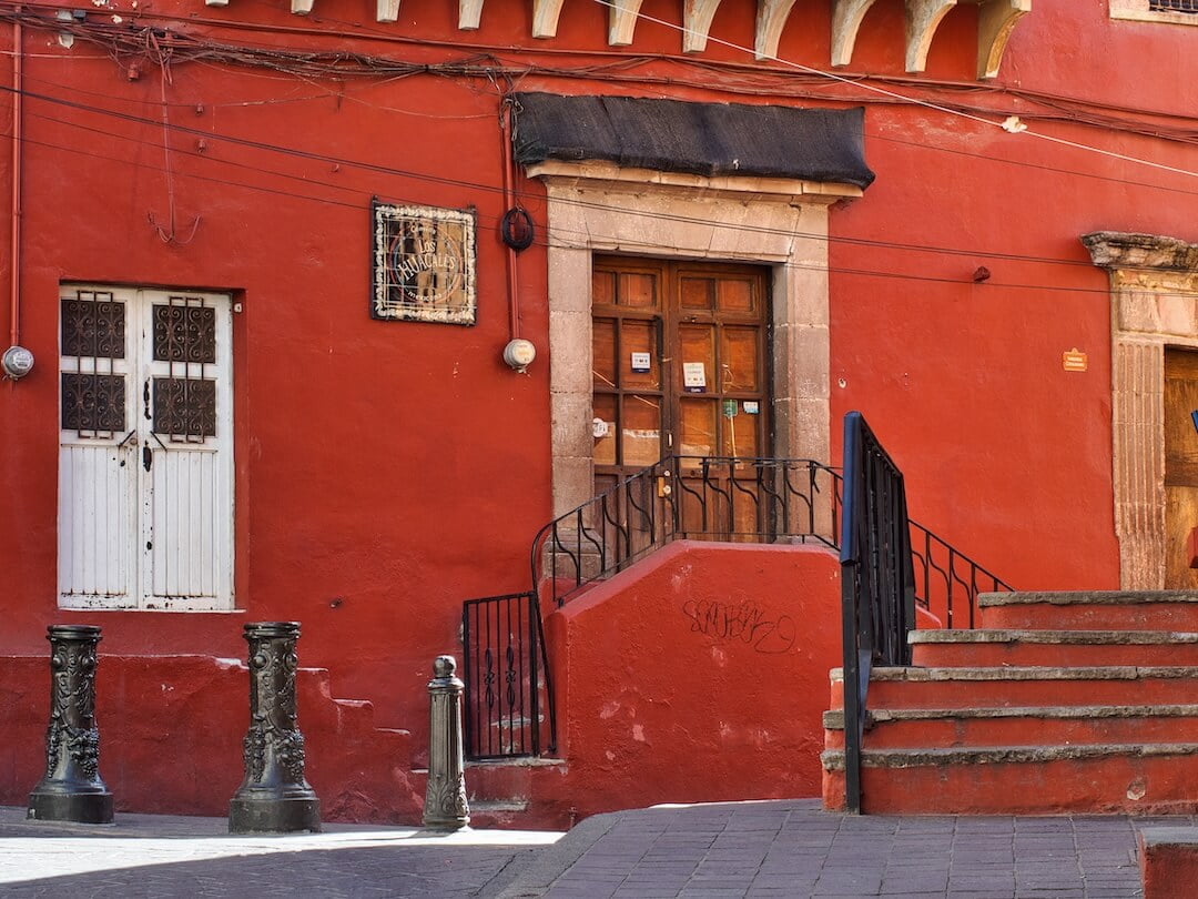 A red building with a studded wooden door