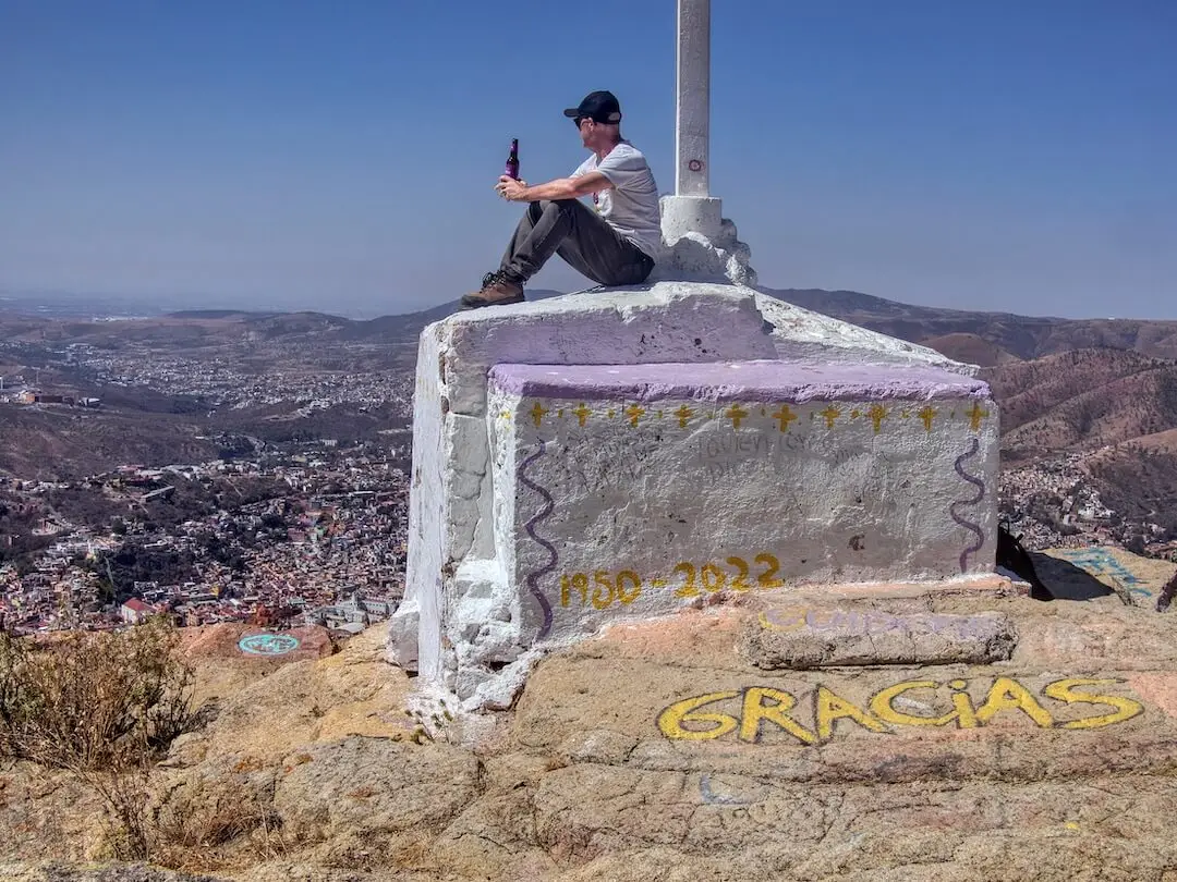 The cross at the summit of Cerro de Sirena - Guanajuato Mexico Ian sits beneath the cross at the summit with a bottle of beer