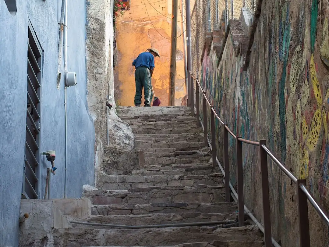 Typical Guanajuato side street - Mexico A man sweeps the pavement in a narrow alley at the top of a set of stone steps