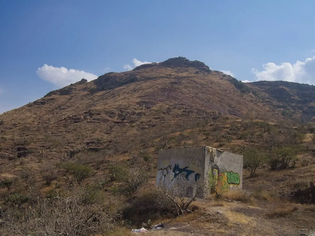 View of Cerro de la Sirena from the abandoned hut - Guanajuato A white concrete hut covered in graffiti stands on a hillside