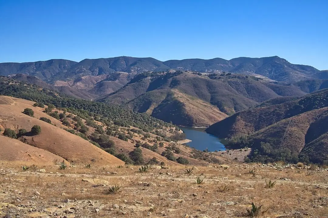 View of Presa de Mata from Cerro de la Sirena Barren mountains in the background with a blue lake in the foreground