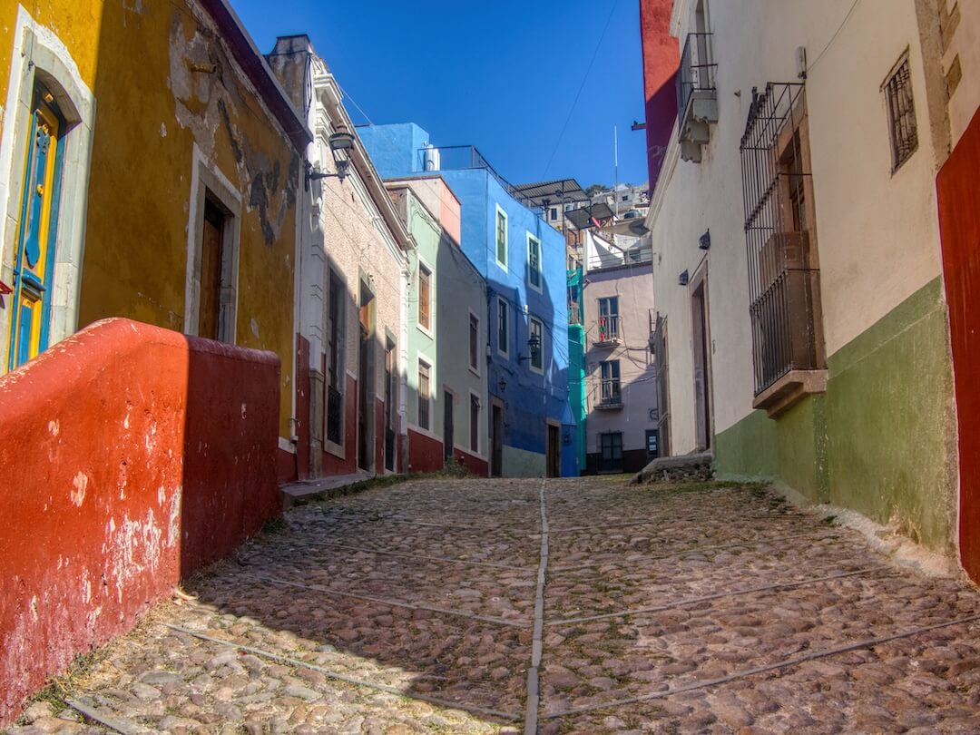A cobbled street flanked by colourful old houses