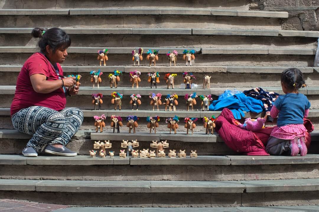 A mother and daughter with toy donkeys on a set of stone steps