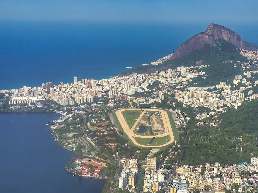Aerial view of a racecourse surrounded by a lake, beach and mountains