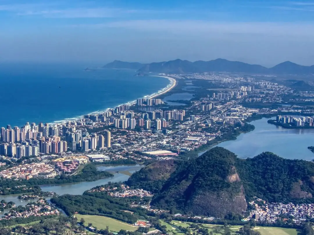 High-rise buildings surrounded by rainforest covered hills, beach and bay