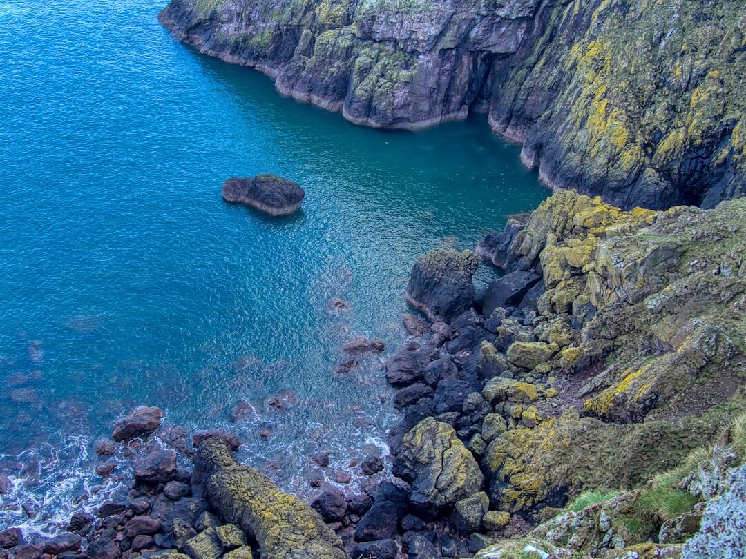 A rocky bay surrounded by yellow moss-covered cliffs