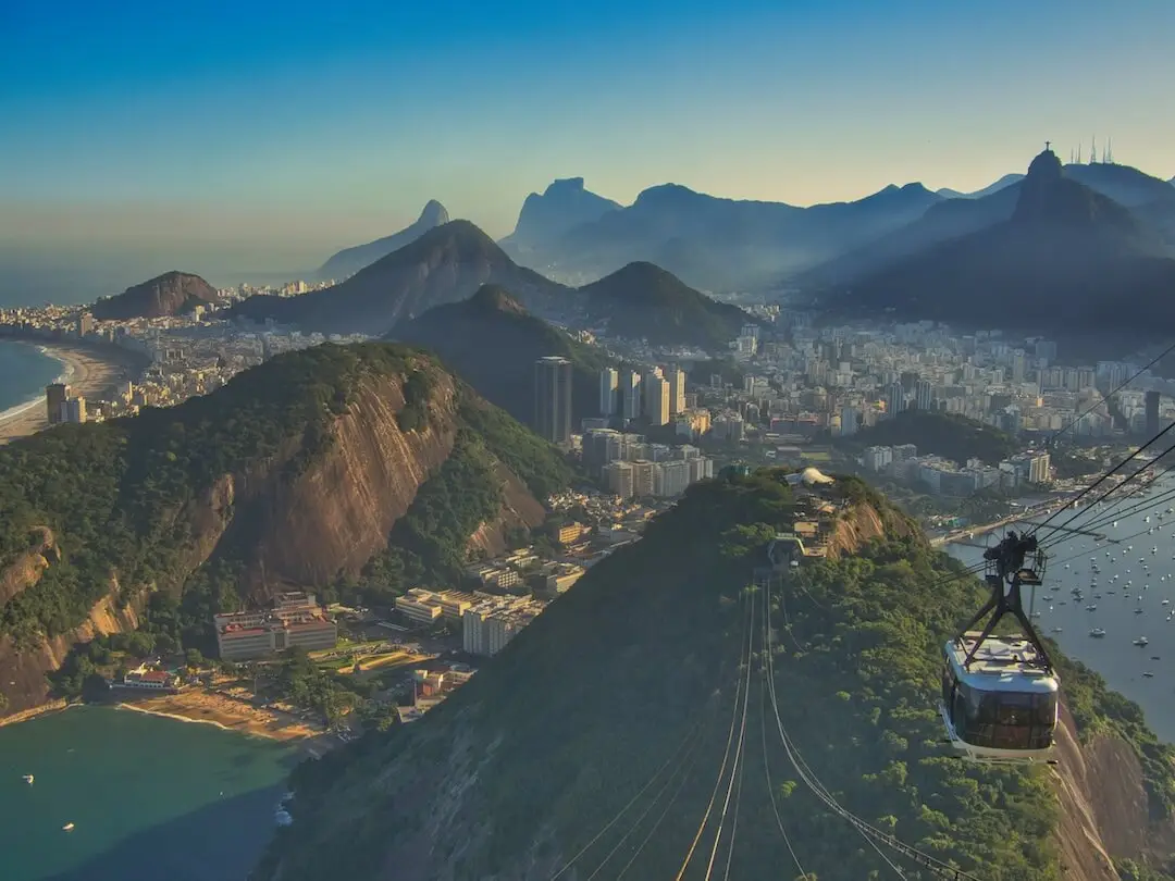 A cable car heads down to a scene of beaches, mountains and city