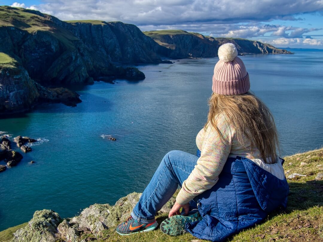 Nicky looks out over a bay with cliffs that stretch into the distance