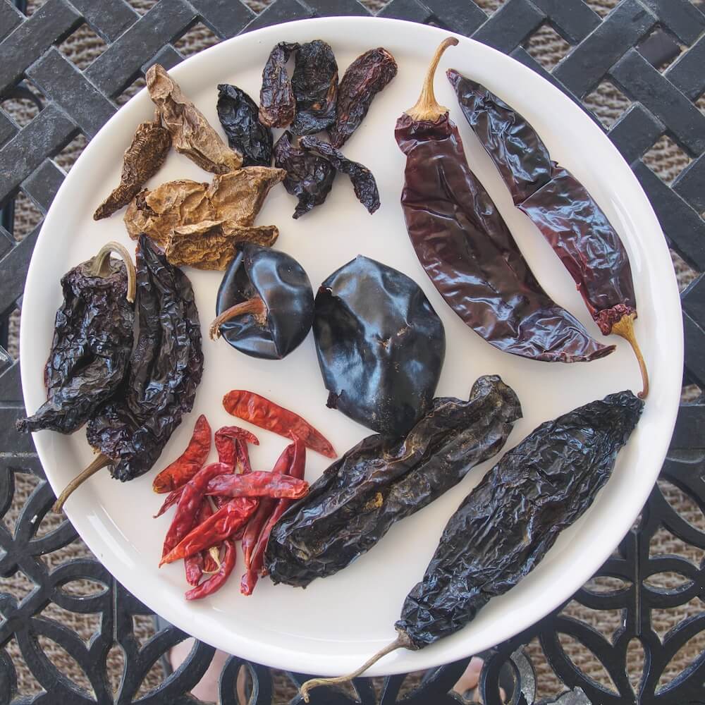 A selection of dried chillies laid on a white plate