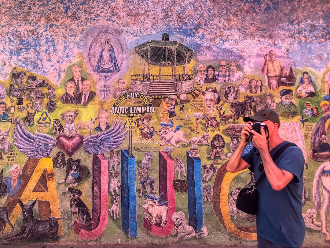 Ian using his camera in front of a mural in Ajijic