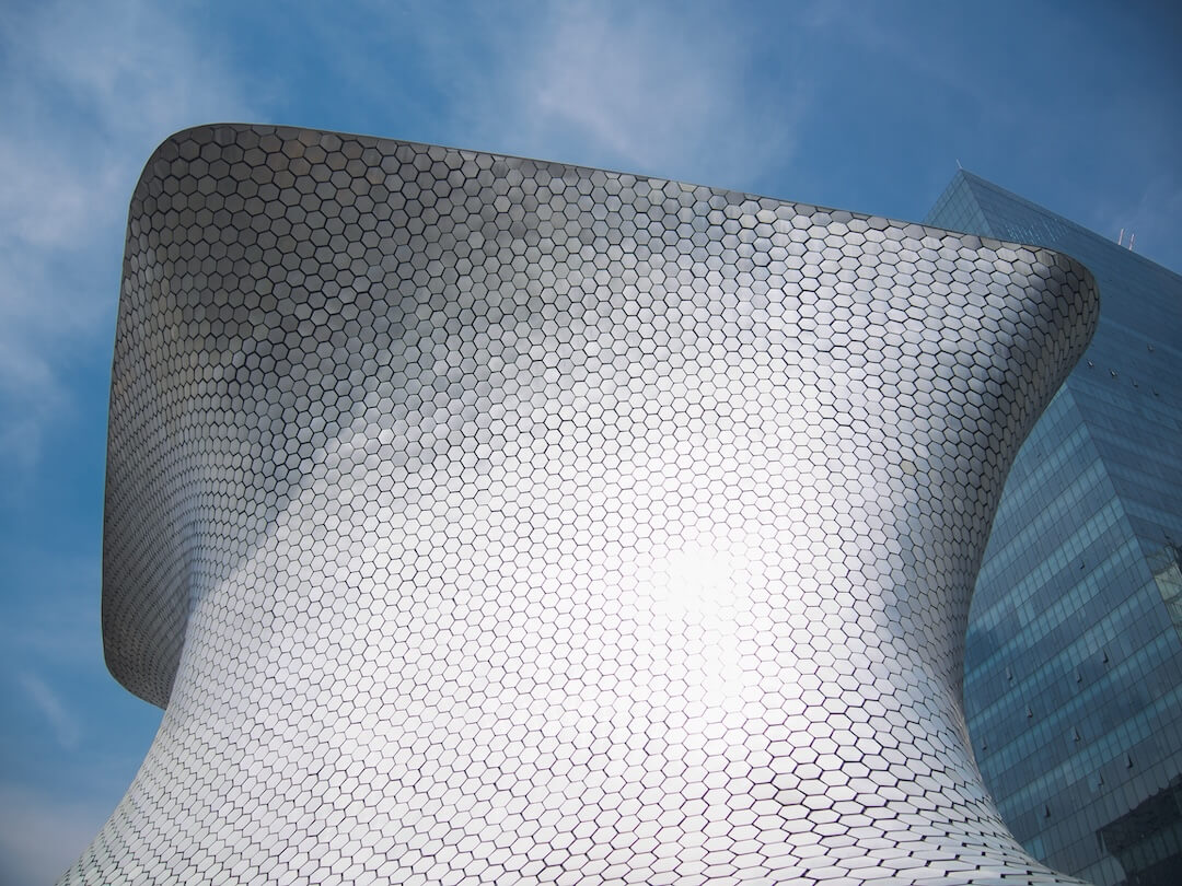 A silver-tiled building with waves and curls in its structure