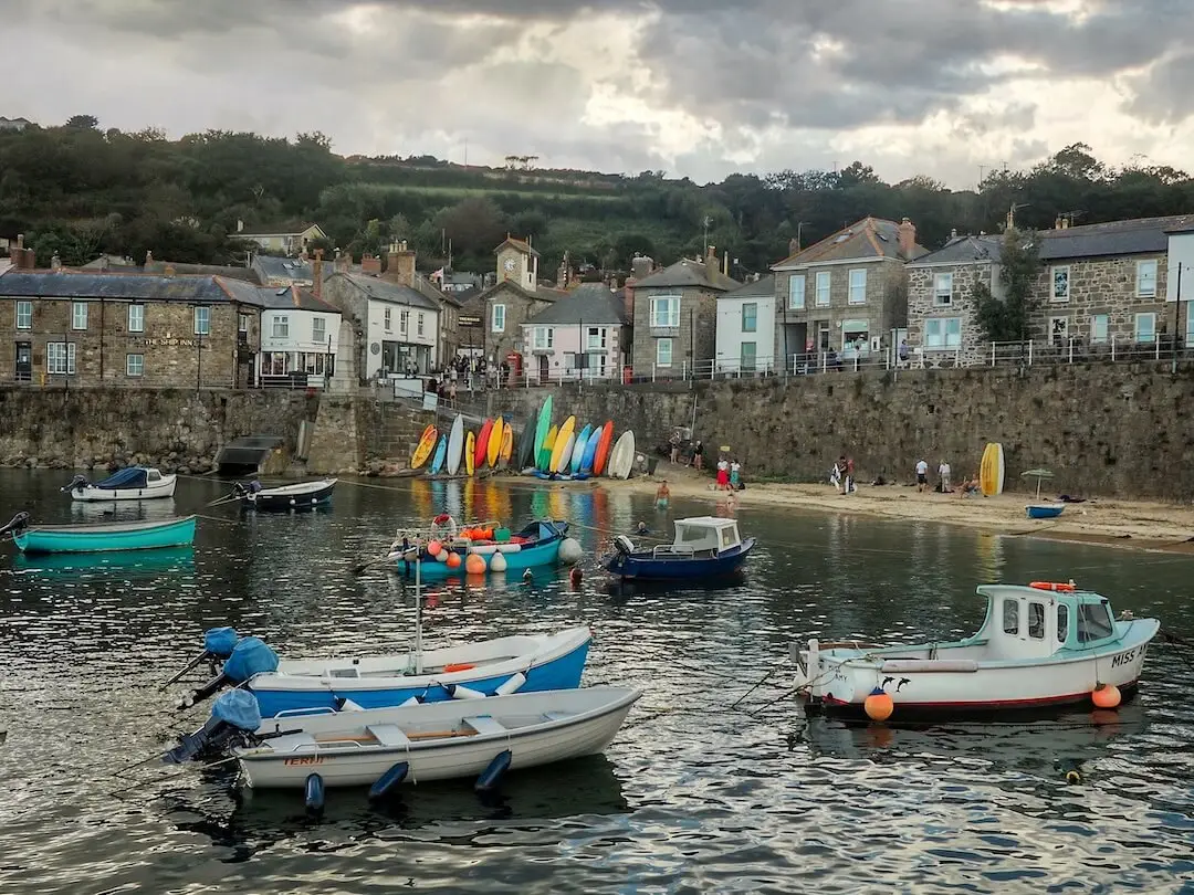 Mousehole - Cornwall Small fishing boats in a harbour with a wall and cottages behind
