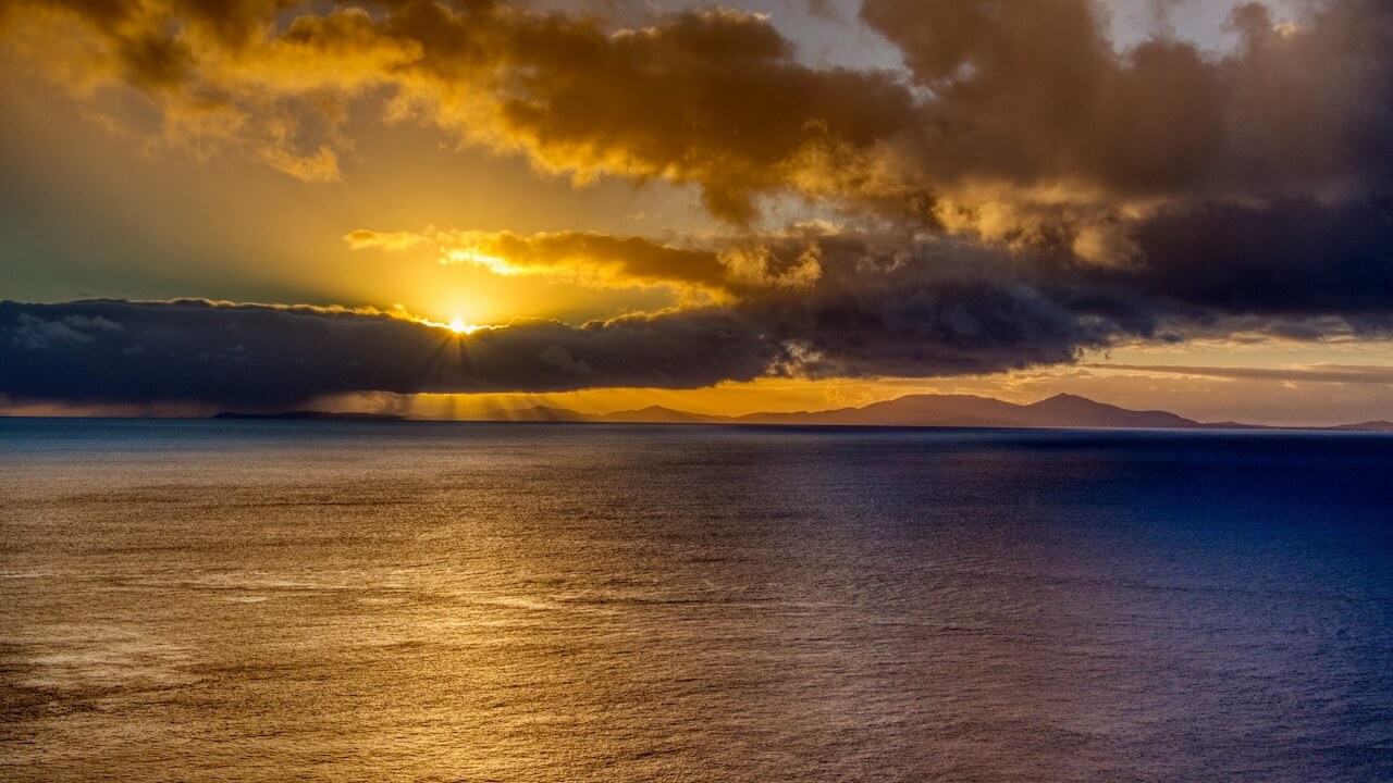 Sunset view over thin rocky peninsula with a lighthouse at its tip