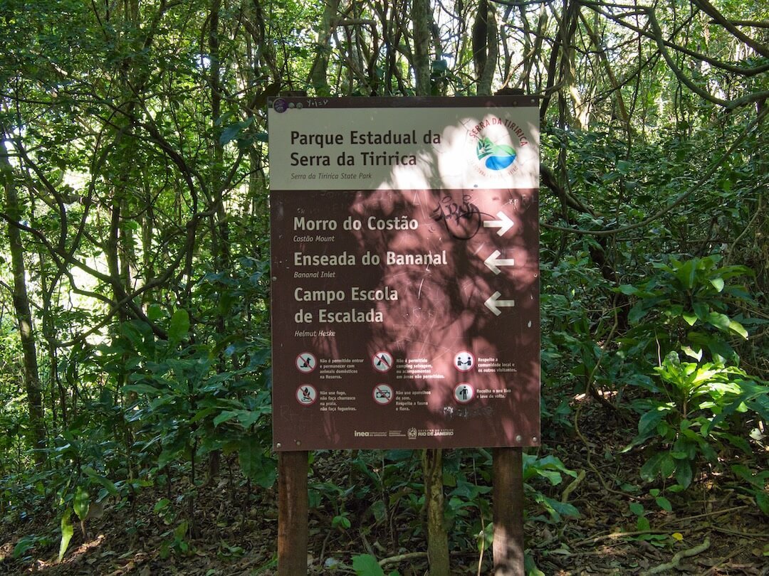 A brown sign with directions set in a forest