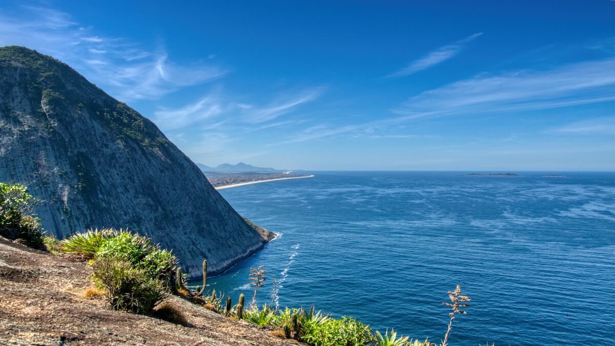 Looking over a cliff and past another headland toward a beach stretching away to the distance