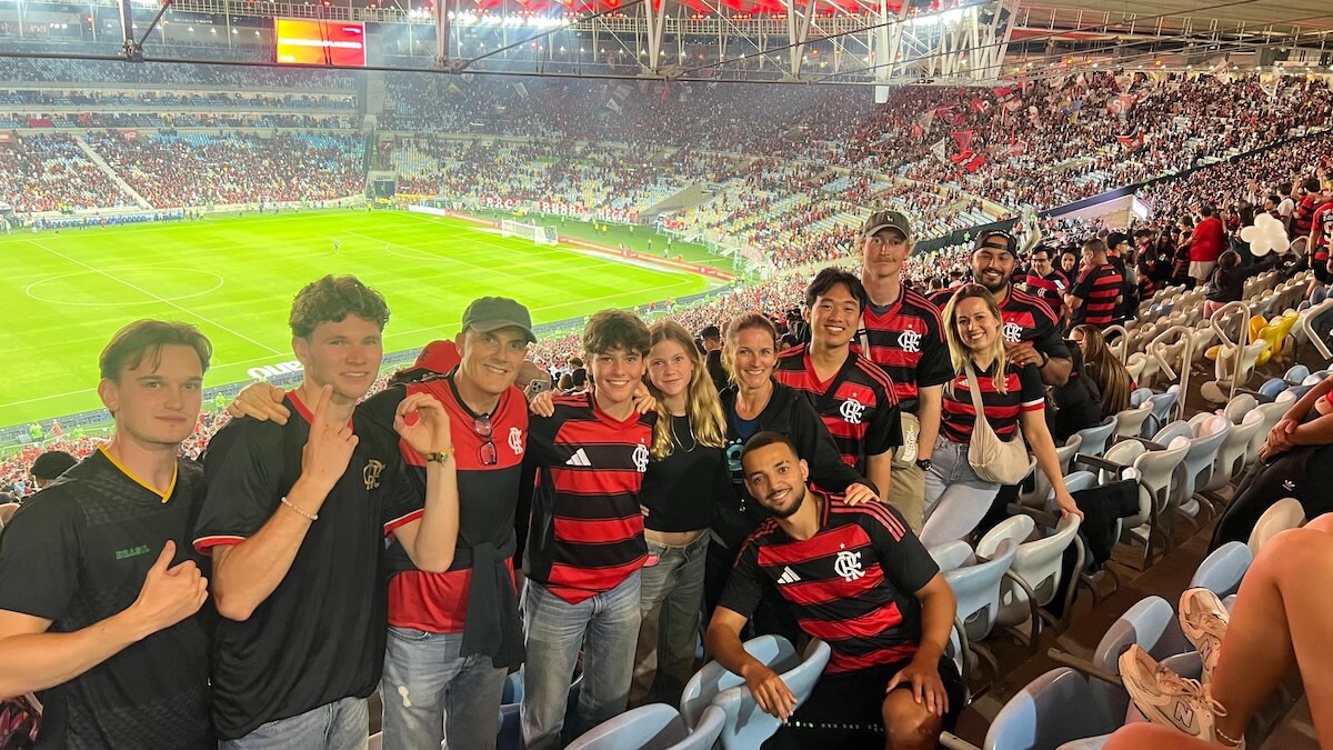 A group of ten people in red and black football shirts at a football stadium
